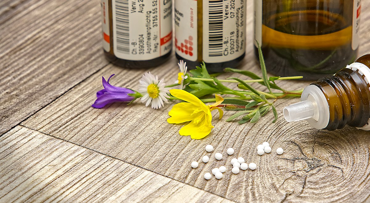 Homeopathic remedy bottles and small white pillules on a wooden table